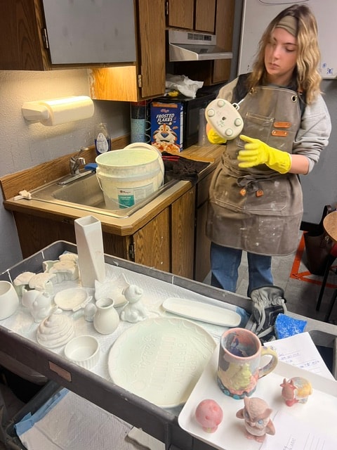 Staff member dipping bisque piece in glaze